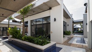 A modern building with a covered outdoor area featuring tiled flooring, planters with greenery, and a clear view of the sky. - Ballito Hills Unit 79 (Ballito)