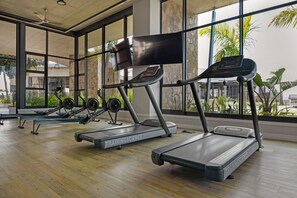 A gym with treadmills, rowing machines, and weights.