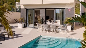 A modern outdoor pool area with a dining set and lounge chairs. - Casa Palmera - Polop, Costa Blanca (Polop)