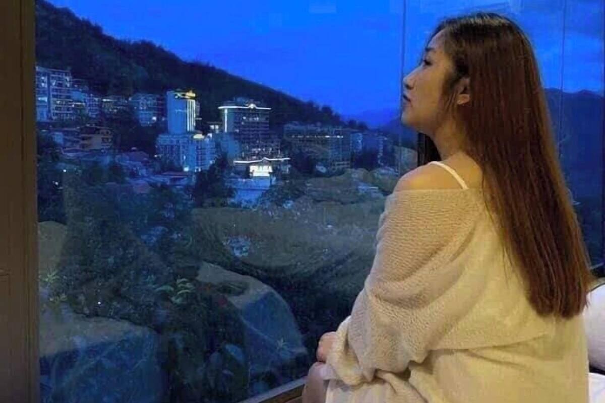 A person sitting by a window overlooking a cityscape at night.