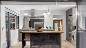 A modern kitchen with a central island, pendant lighting, and a built-in washing machine.