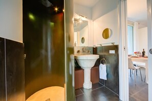 Et moderne badeværelse med et fritstående håndvaskarrangement, et stort spejl og en kommode med et håndklædestativ.