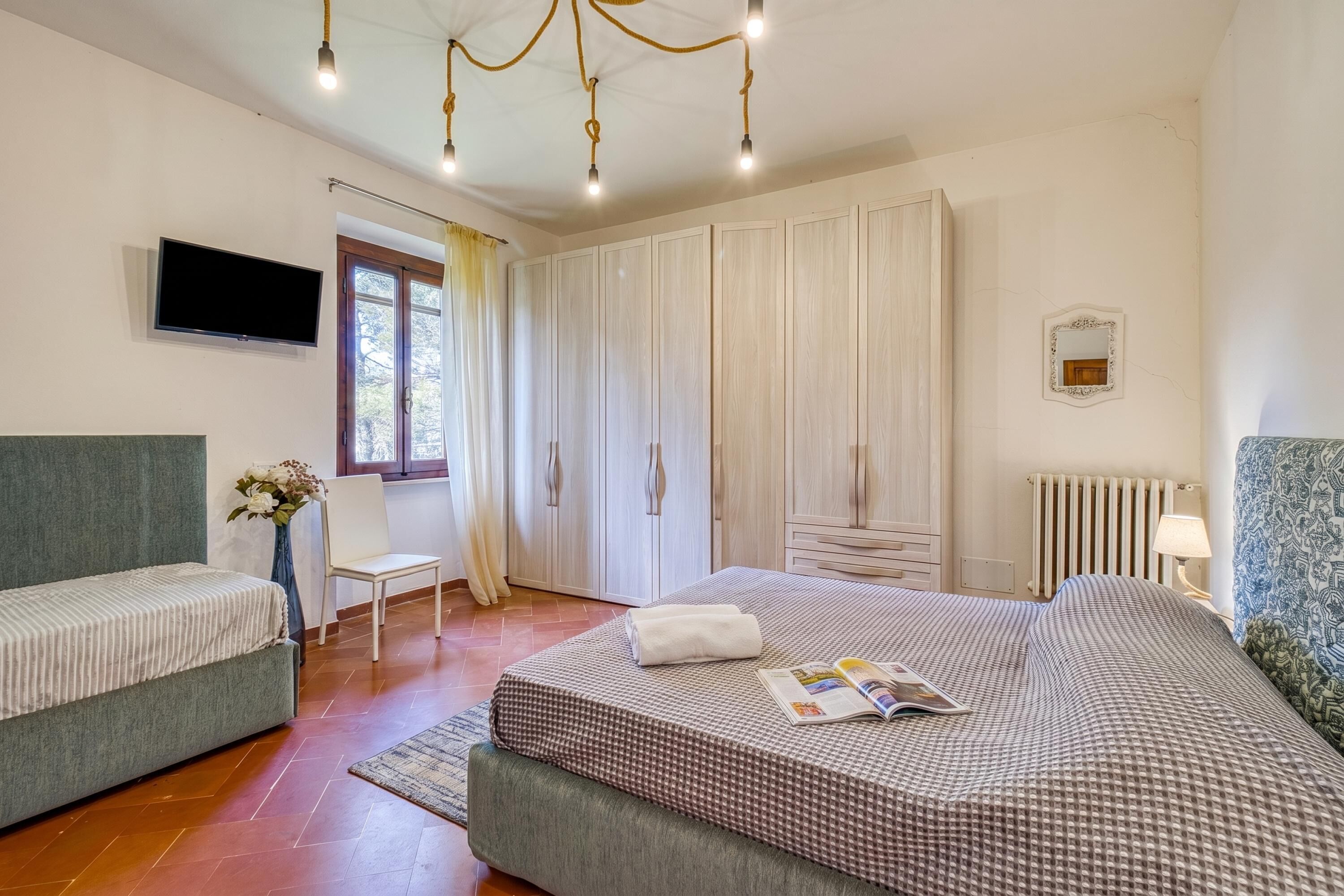 Un dormitorio con cama, sofá, televisión, armario y ventana.
