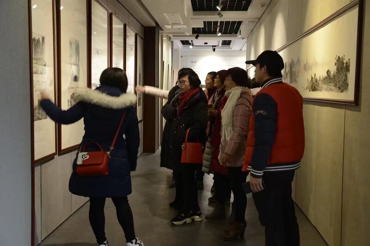 A group of people in a hallway with framed artworks on the walls.