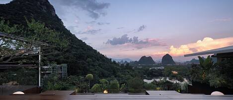 A rooftop terrace with a view of a mountainous landscape and a river.