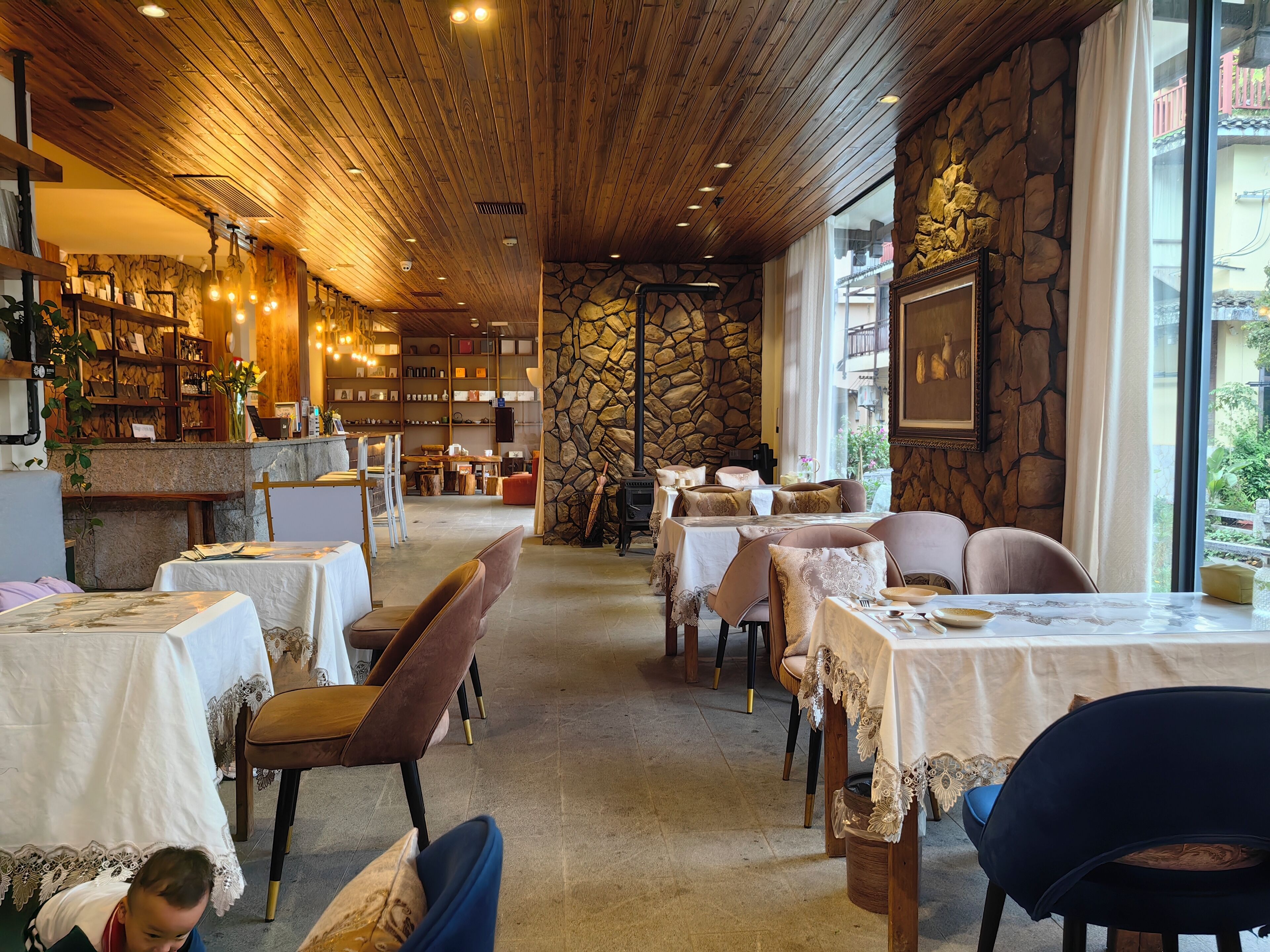 A restaurant with wooden ceiling, stone walls, and tables set for dining.