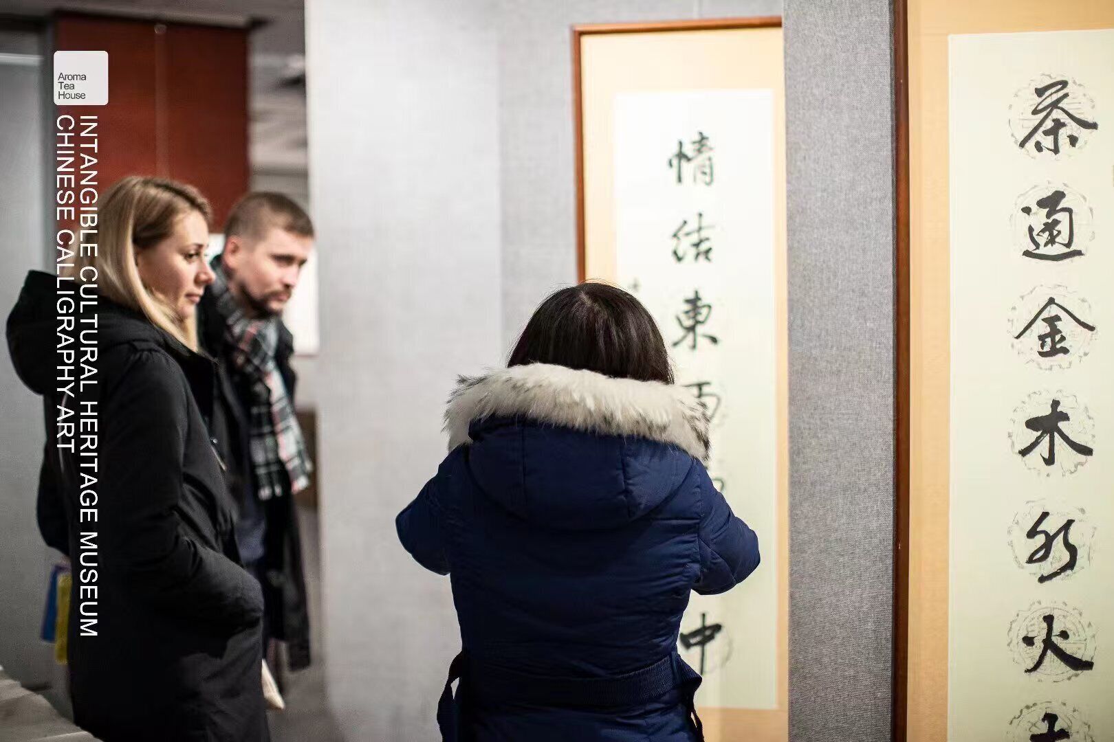 A group of people viewing calligraphy art in a museum setting.