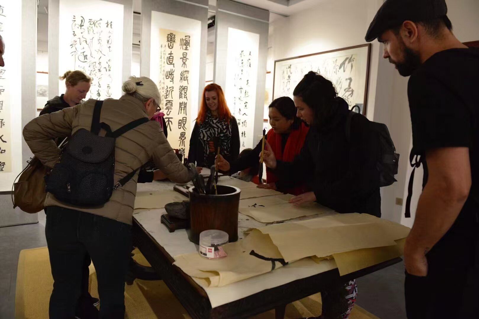 A group of people engaged in a calligraphy activity at a table with calligraphy tools and paper.