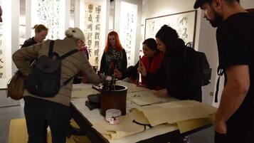 A group of people engaged in a calligraphy activity at a table with calligraphy tools and paper.
