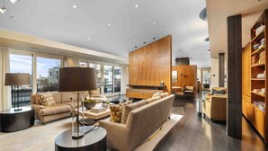 A spacious living room with a large sofa, a coffee table, and a bookshelf. - Luxury Penthouse Living, Breathtaking Views, Huge Wraparound Deck, All New Decor, Two Parking Spots (Portland)