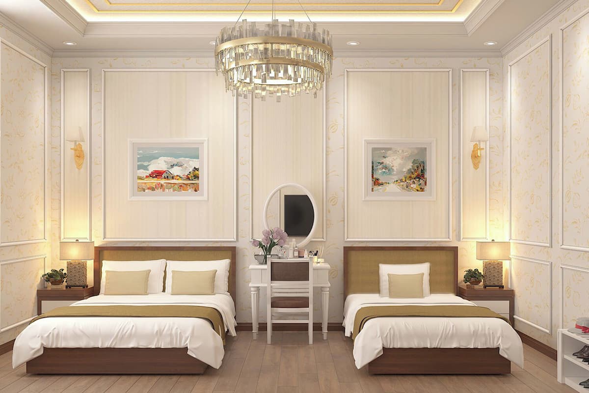 A hotel room with two beds, a desk, and a chandelier.