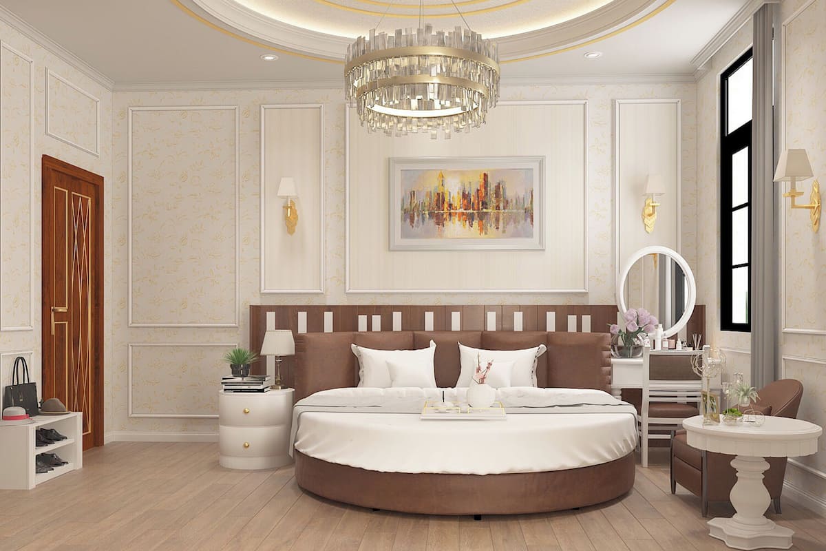 A luxurious bedroom with a large round bed, a chandelier, a painting, and a vanity with a mirror.