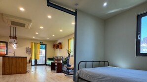 A room with a bed, a desk, and a chair. There is a window with a view of buildings. - Hongdae Private Guesthouse (Seoul)