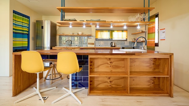 A modern kitchen with a wooden island, two yellow chairs, and a stainless steel refrigerator. - Hongdae Private Guesthouse (Seoul)