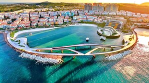 Un paisaje urbano costero con un puerto deportivo destacado, un puente y edificios residenciales.