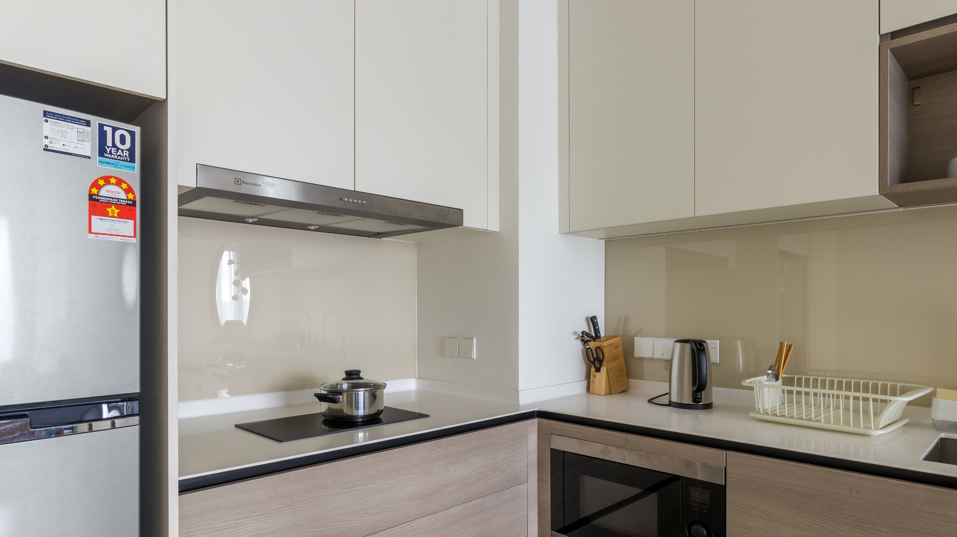 A modern kitchen with a stainless steel refrigerator, a built-in oven, and a microwave.