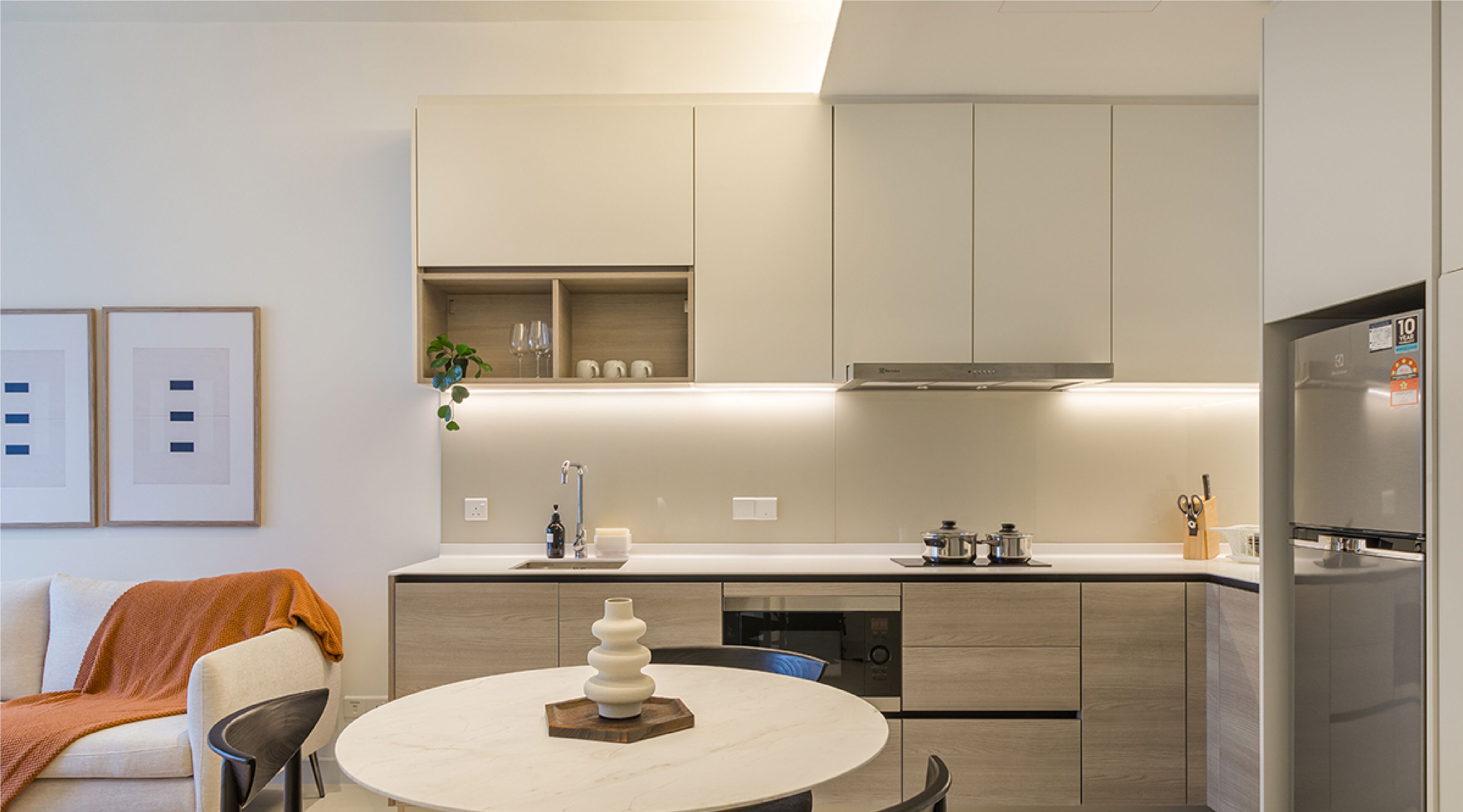 Una cocina moderna con una isla central, electrodomésticos integrados y un comedor con una mesa redonda.