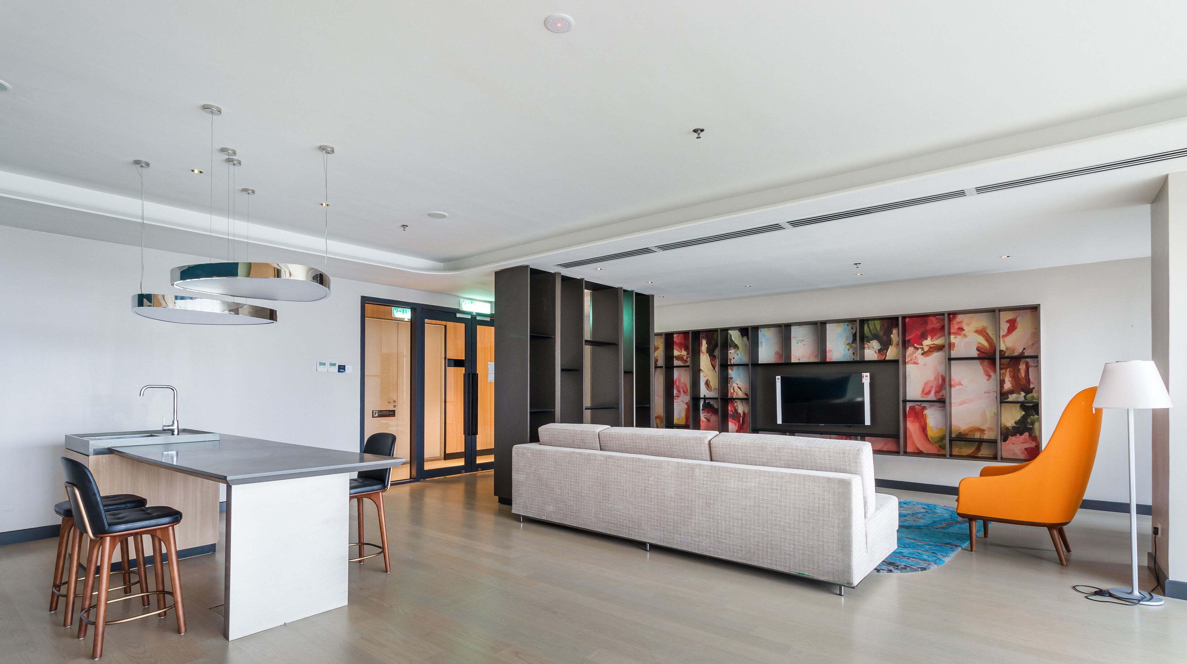 Una sala moderna con un sofá, un televisor y un comedor con barra.