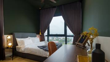 Una habitación de hotel con cama, escritorio, lámpara, un florero con flores y vistas a la ciudad a través de la ventana.