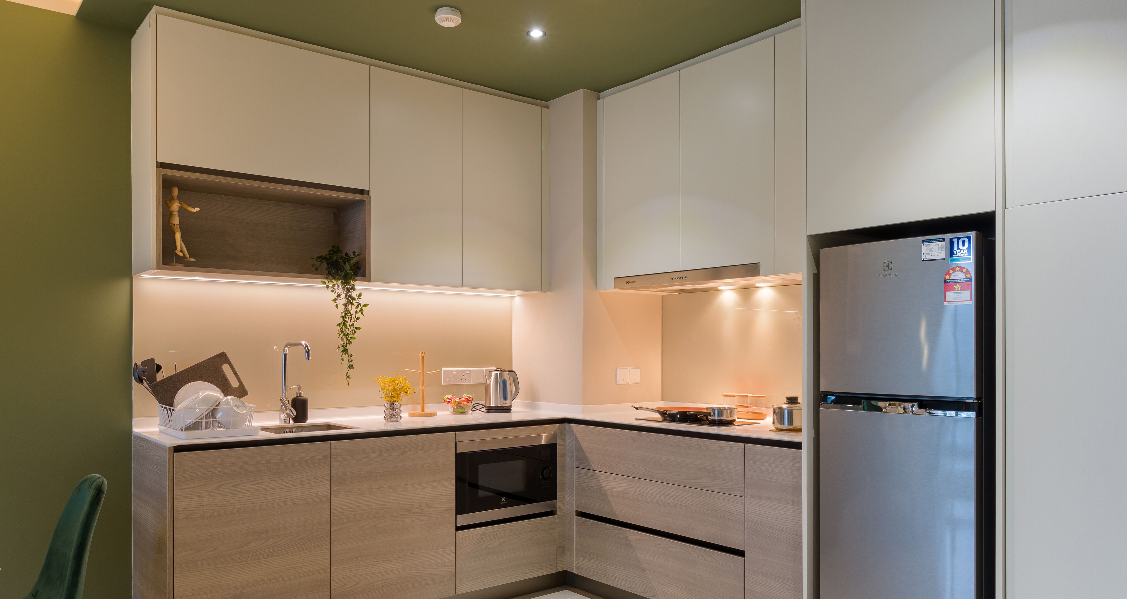 A modern kitchen with built-in appliances, a wooden cabinet, and a countertop with a kettle and a cutting board.