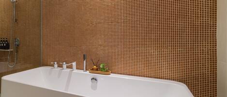 Une salle de bain moderne avec une grande baignoire, une douche et un mur recouvert de carreaux.