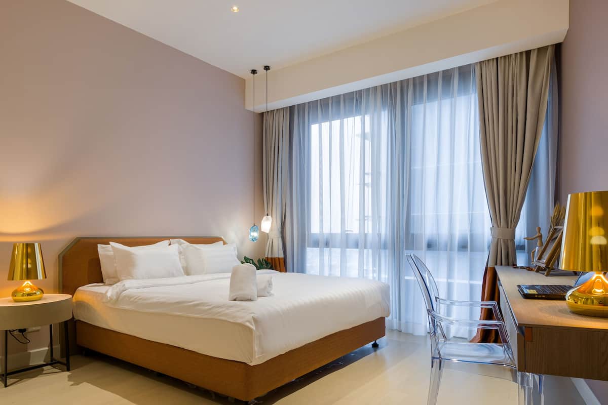 Habitació d'hotel moderna amb un llit gran, una taula de treball i una cadira.