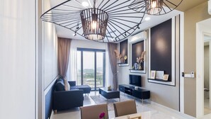 Una sala de estar moderna con sofá, mesa de centro y mueble para la televisión. Hay una ventana grande con cortinas y una lámpara en el techo.