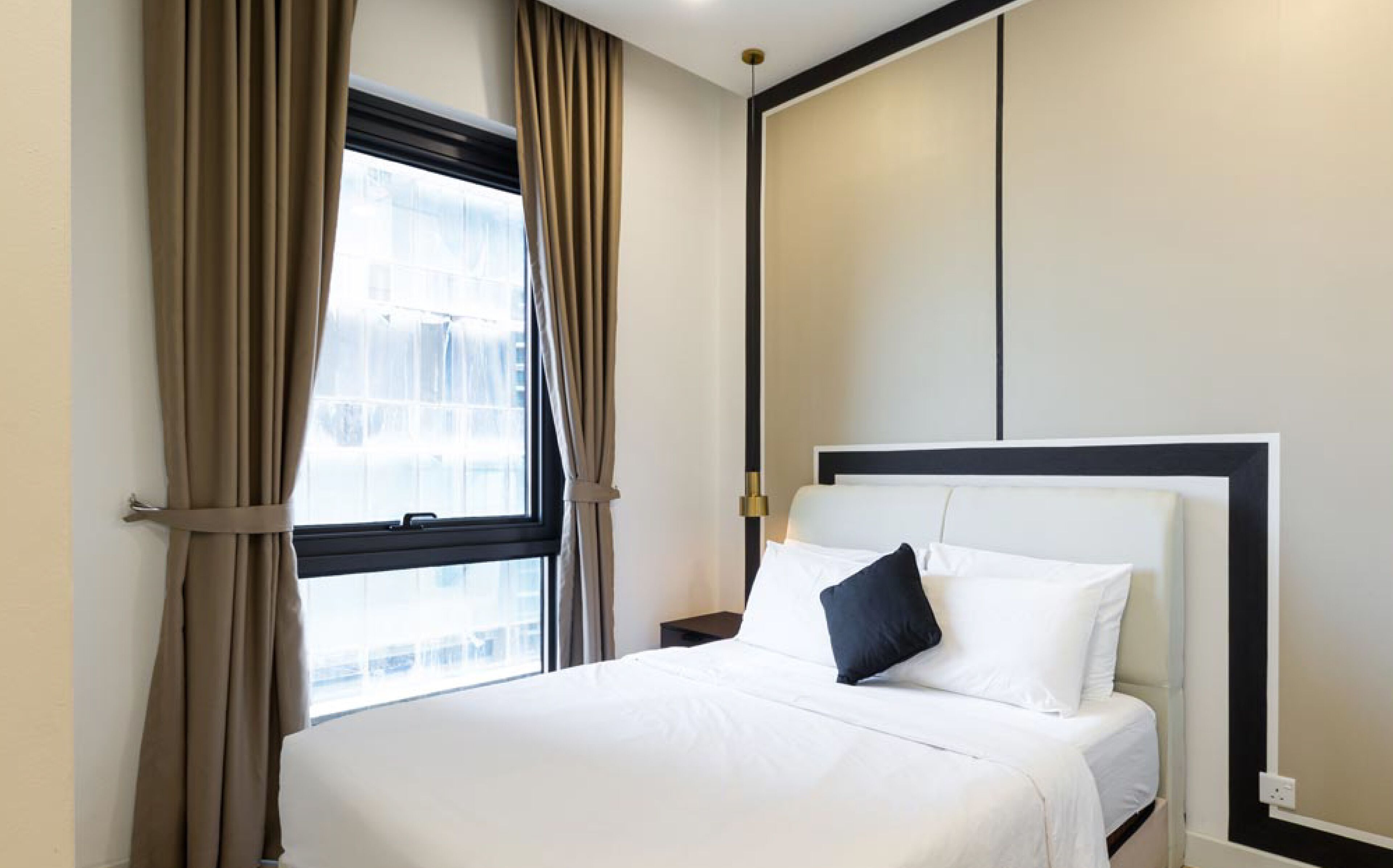 A hotel room with a large bed, a nightstand, and a window with curtains.