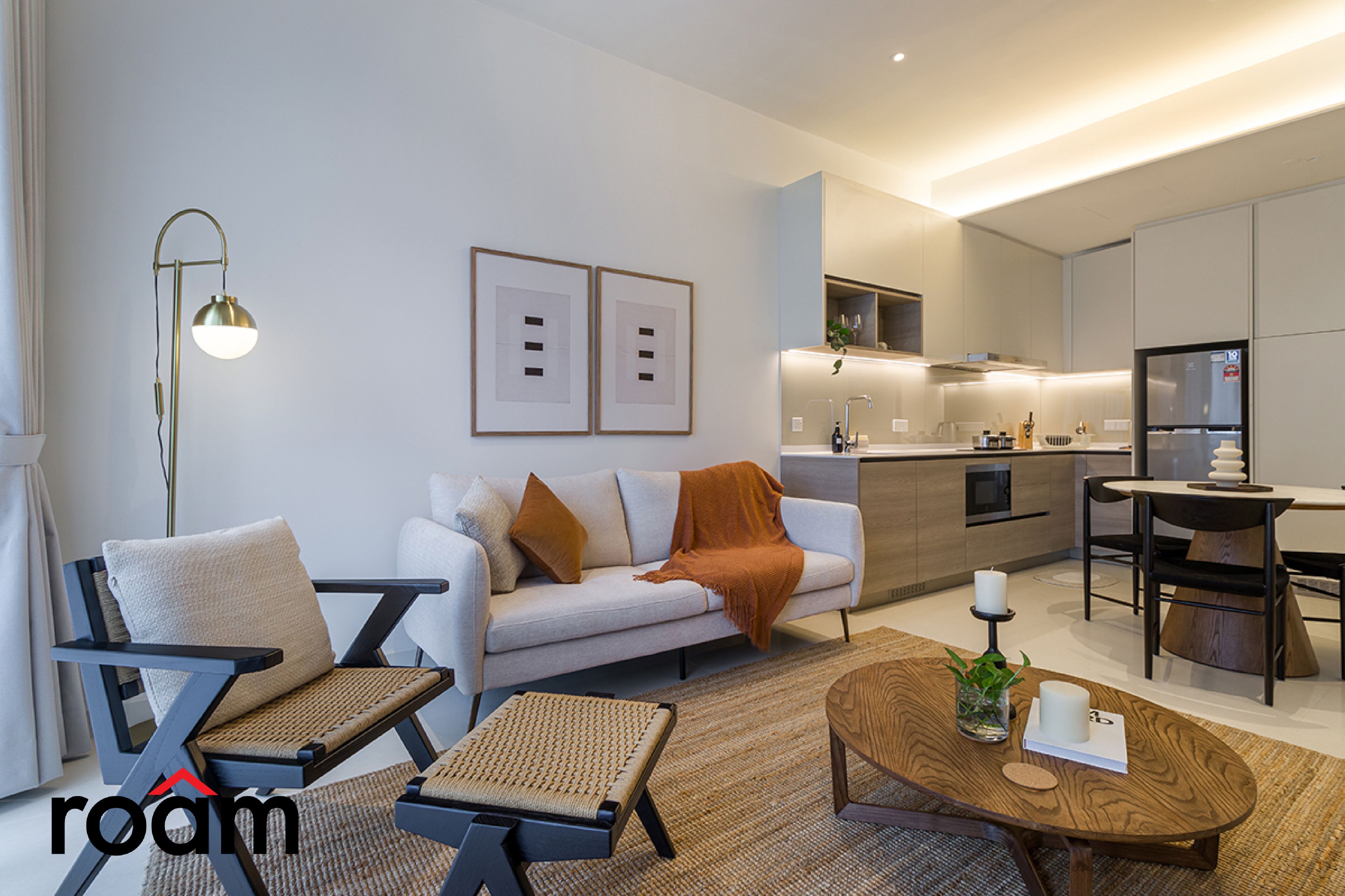 A modern living room with a sofa, armchairs, a coffee table, and a dining area with a table and chairs.