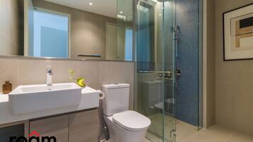 A modern bathroom with a glass-enclosed shower, a white sink, and a toilet.