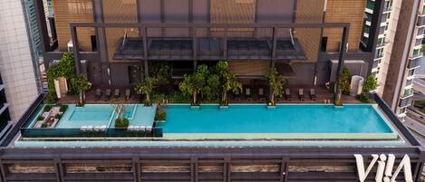 A modern building with a rooftop pool, balconies, and a sign that reads "VIA".