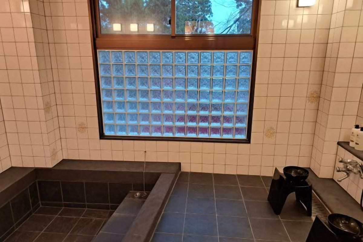 Casa de banho com banheira, janela de vidro jateado e paredes revestidas a azulejos.