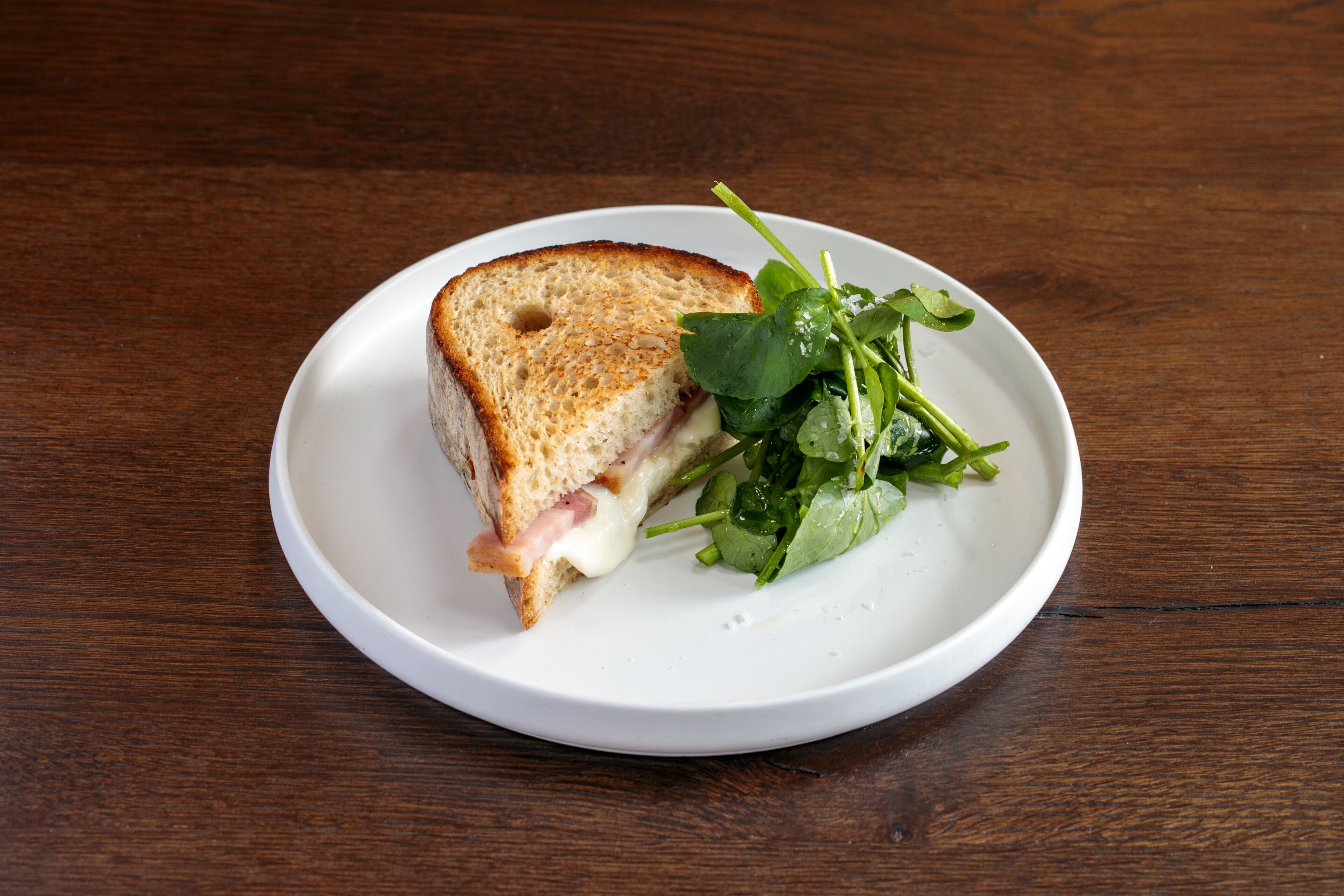 A sandwich on a white plate with a wooden table background.