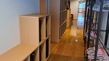 A hallway with wooden flooring, metal shelving units, and a rack of hanging clothes.