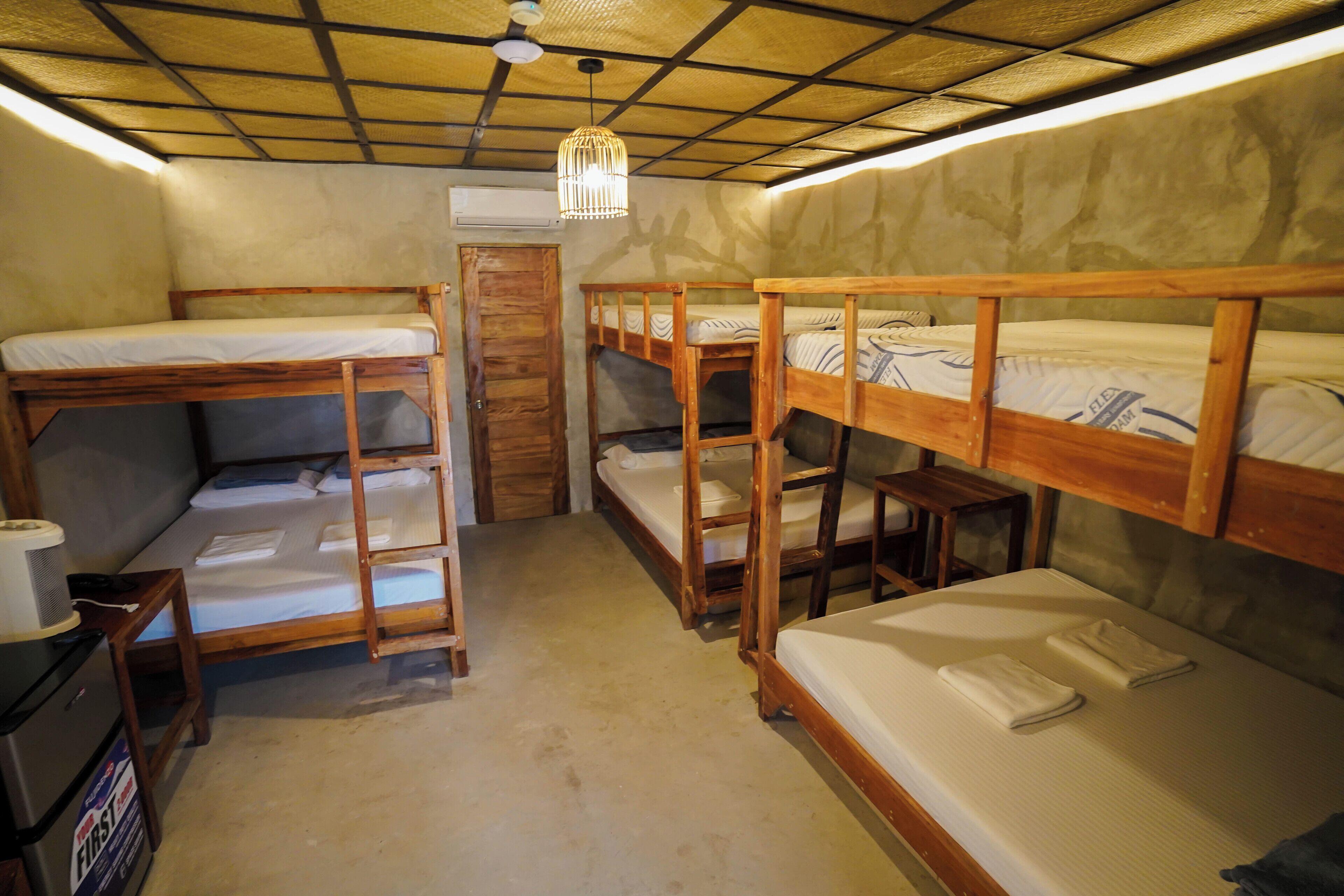 Habitación tipo dormitorio con literas, ventilador de techo y una mesita con una radio.