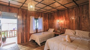 Una habitación de madera con dos camas, un banco y una ventana con cortinas.