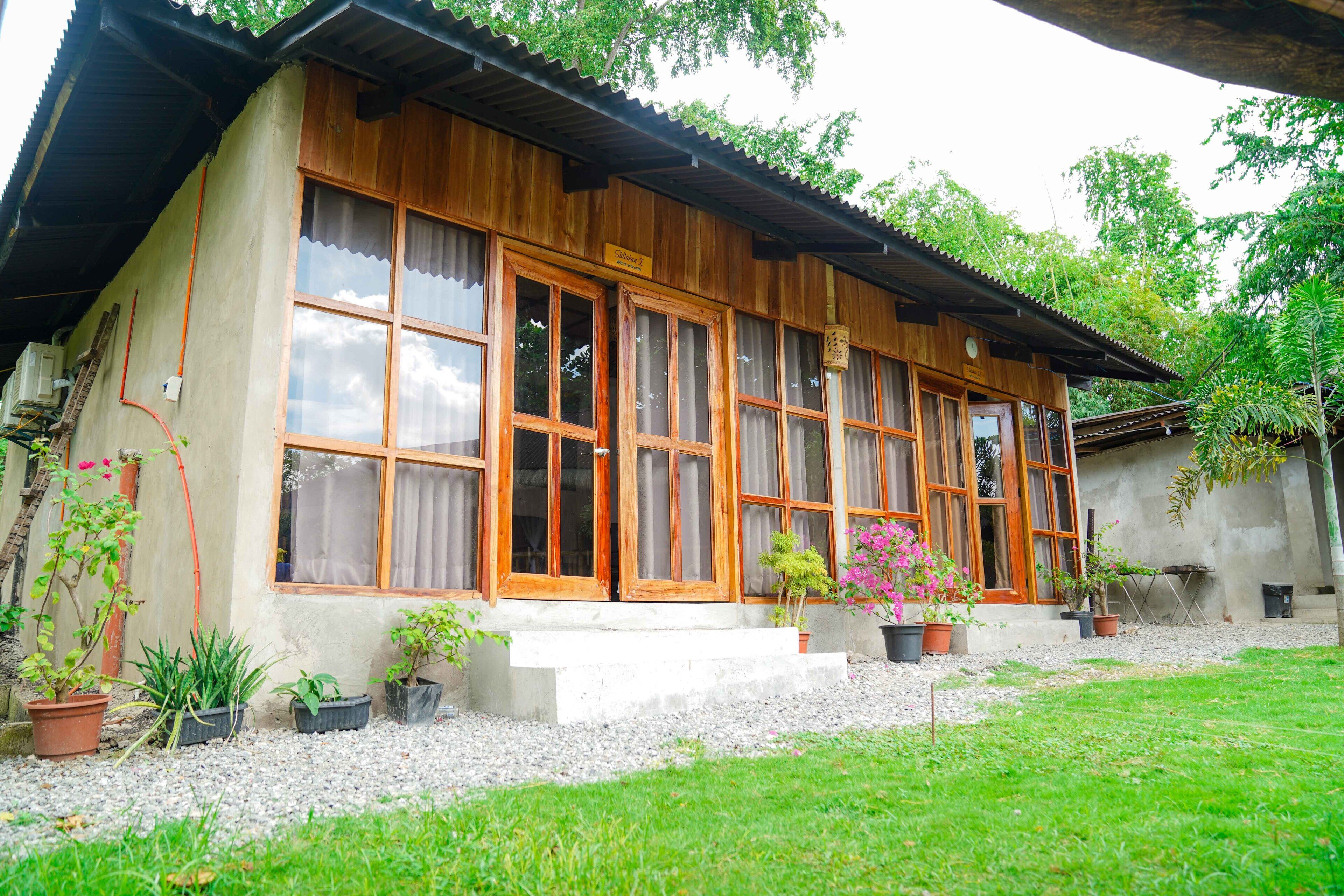Une maison en bois avec de grandes fenêtres et un petit porche.