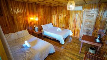Habitación de cabaña de madera con dos camas, una mesita pequeña y una lámpara colgante.