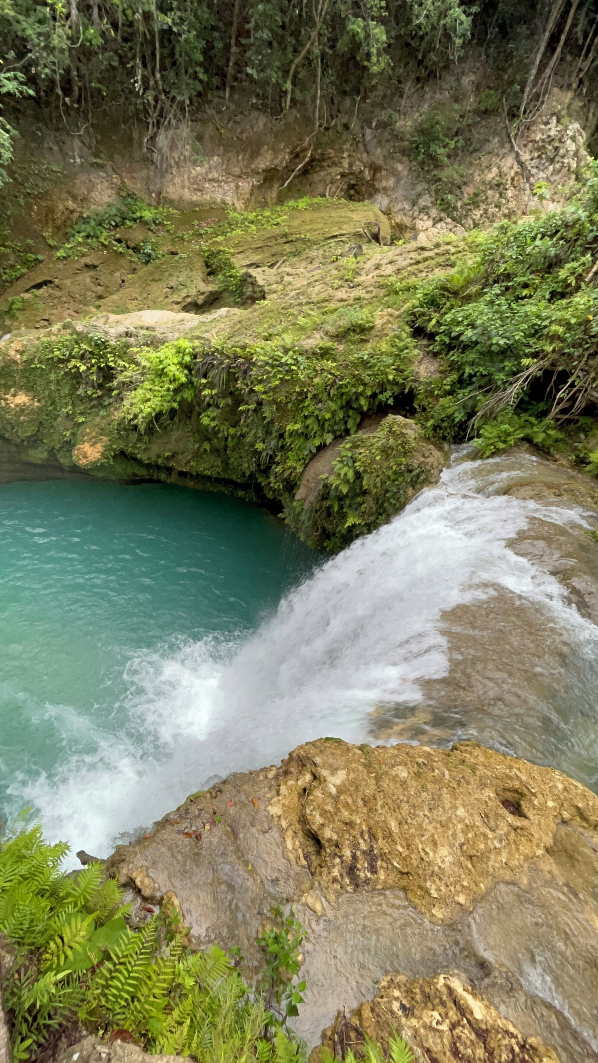 A natural landscape with a waterfall, rocky terrain, and lush greenery.