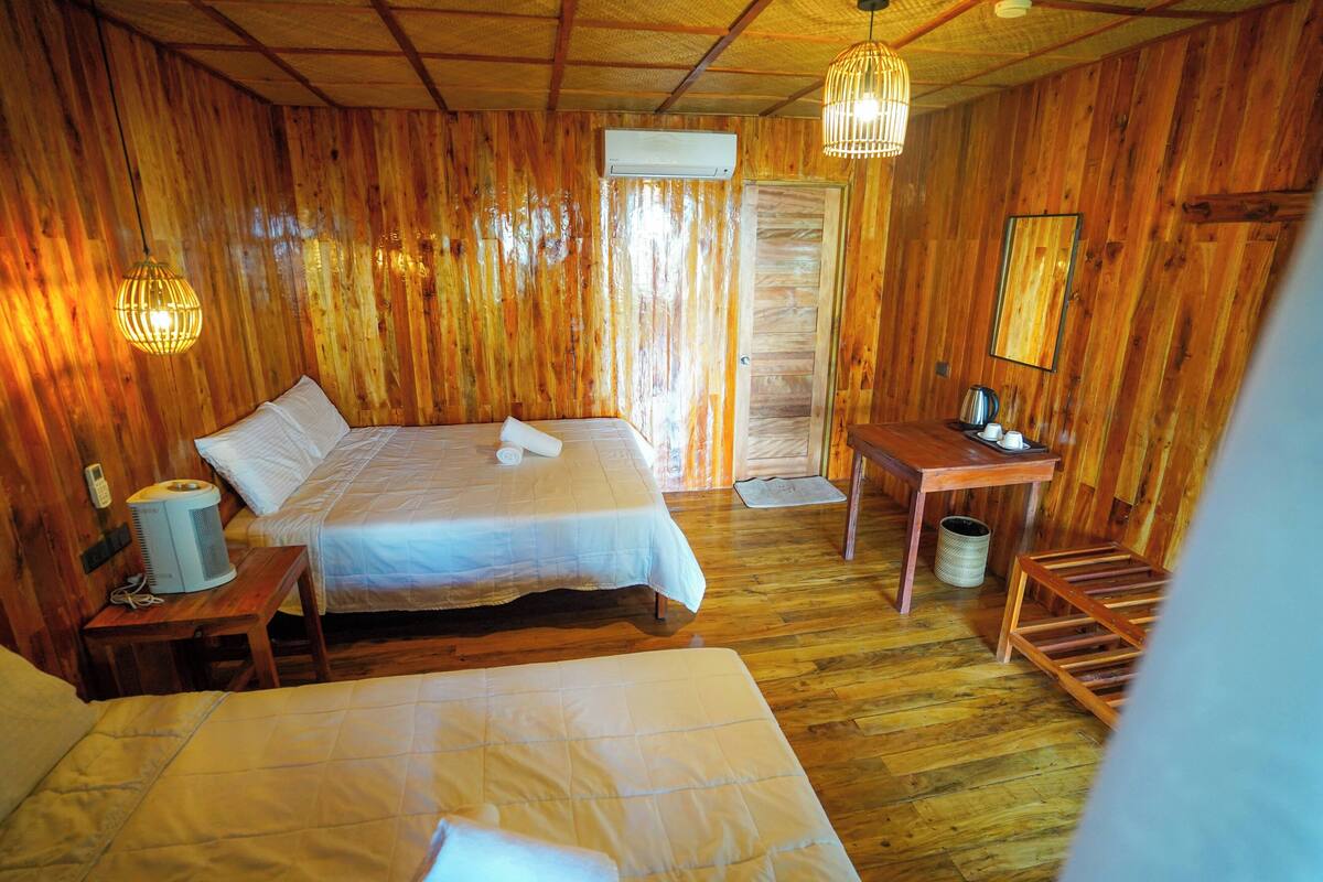 Una habitación de madera con dos camas, un escritorio y una silla.