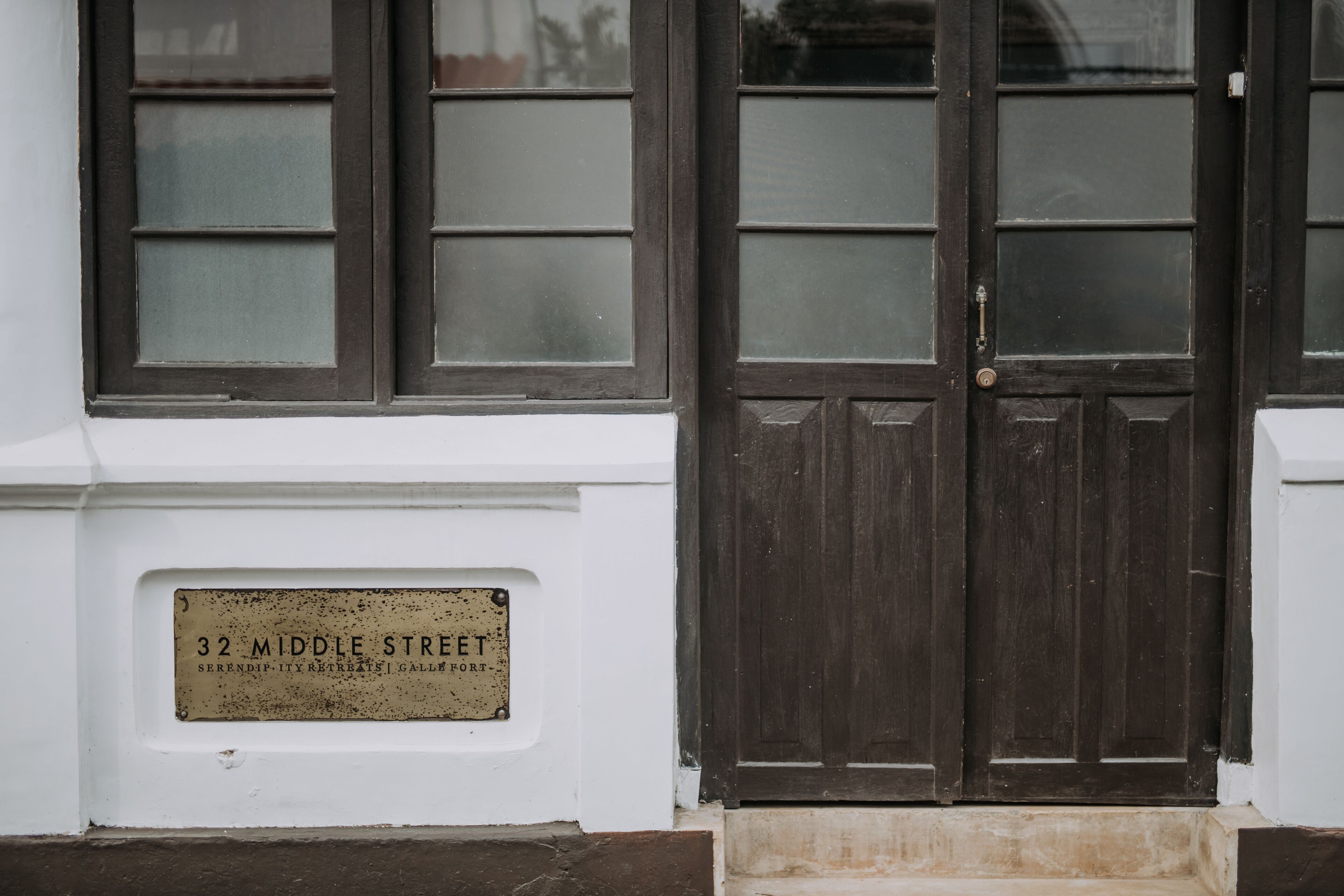 Une façade d’immeuble avec une porte en bois foncé et une enseigne indiquant « 32, rue Middle ».