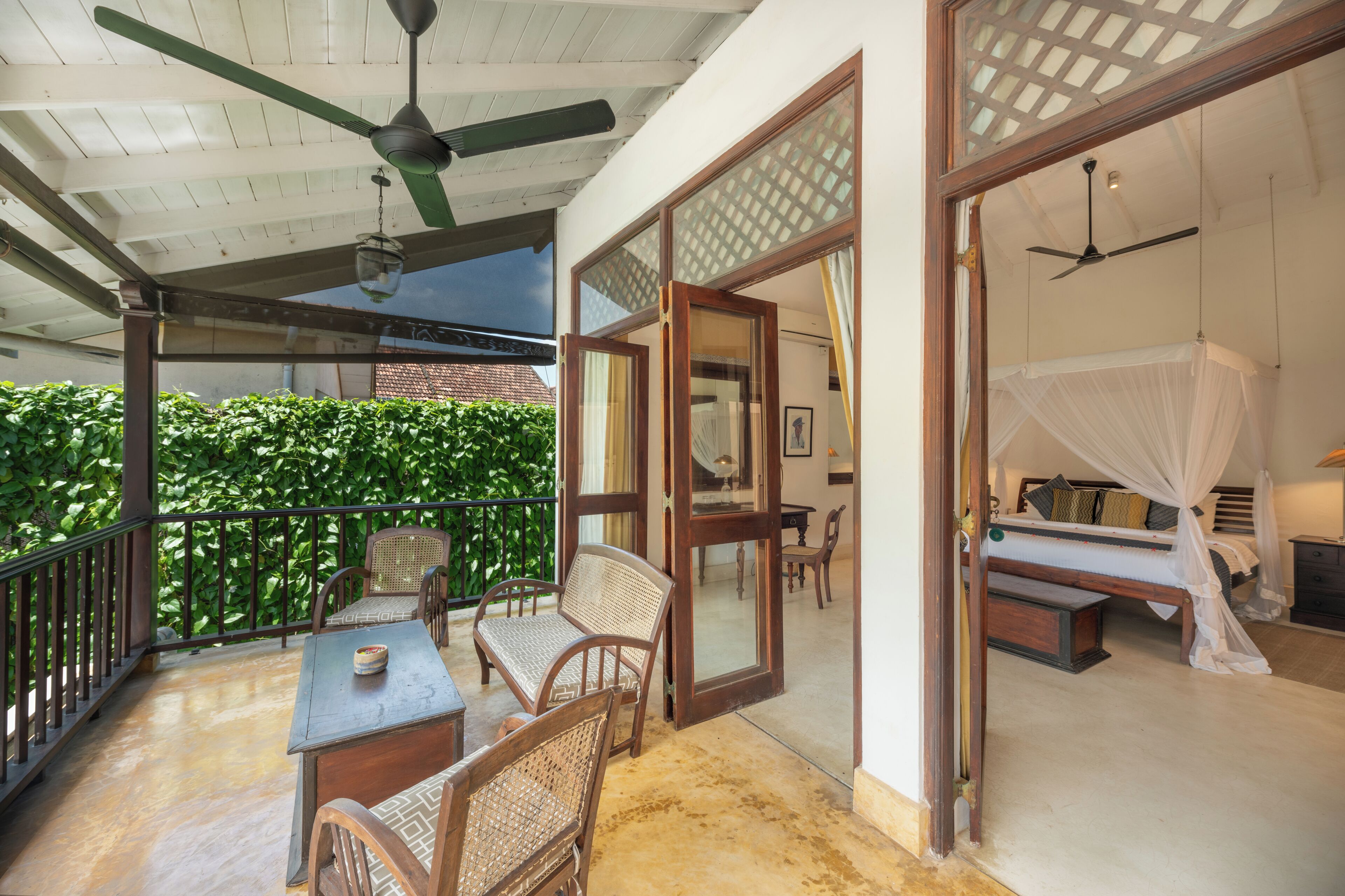 Una habitación con cama, ventilador de techo y balcón con sillas y mesa.
