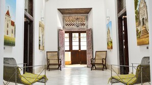 A spacious hallway with two chairs and a wooden ceiling, leading to a door with a decorative lattice. - 32 Middle Street (Galle)