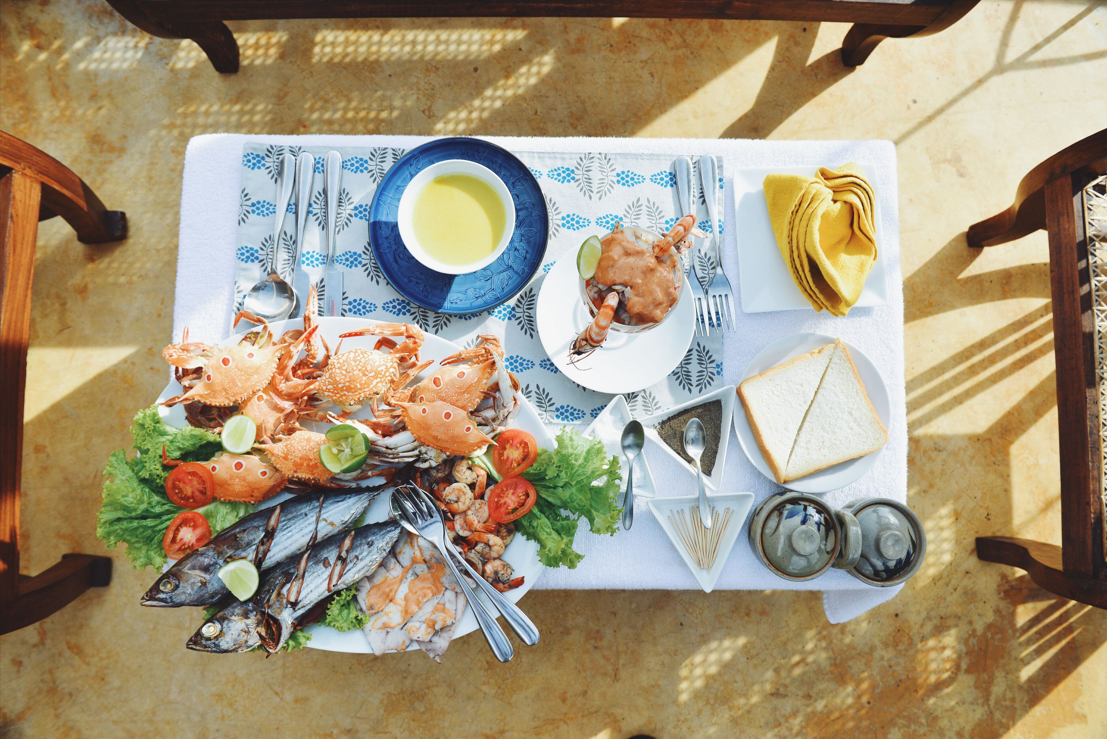 Una mesa servida con mariscos, pan y salsas.