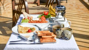 A breakfast setup on a wooden deck with a table, chairs, and a view of a lounge area. - 32 Middle Street (Galle)