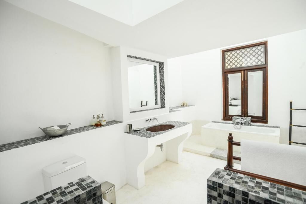 Un baño moderno con un espejo grande, dos lavamanos, una bañera y un inodoro.