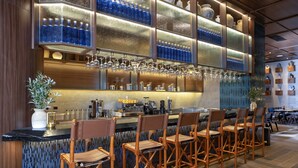 A bar area with a long counter, multiple stools, and a variety of glassware and bottles.