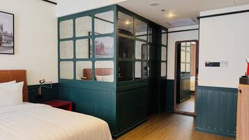 Habitación de hotel con una cama grande, una mesita de noche, un aparador, un espejo y vistas al exterior a través de una ventana con marco verde.