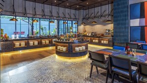 A modern restaurant with a central bar area, seating arrangements, and large windows providing natural light.