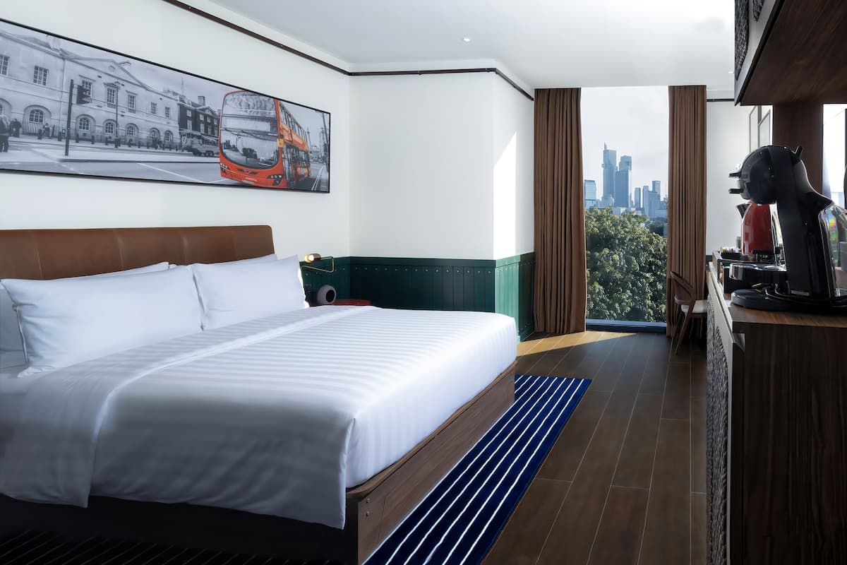 Une chambre d’hôtel avec un grand lit, une vue sur la ville, une machine à café et un tableau au mur.